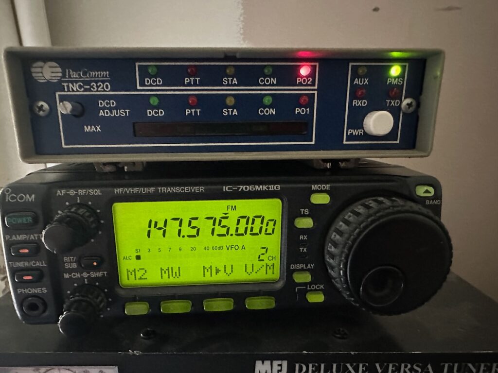 Initial Packet Radio Setup, a PacComm TNC-320 attached to an Icom IC-706MkIIg, both powered on with the radio n 147.575Mhz FM